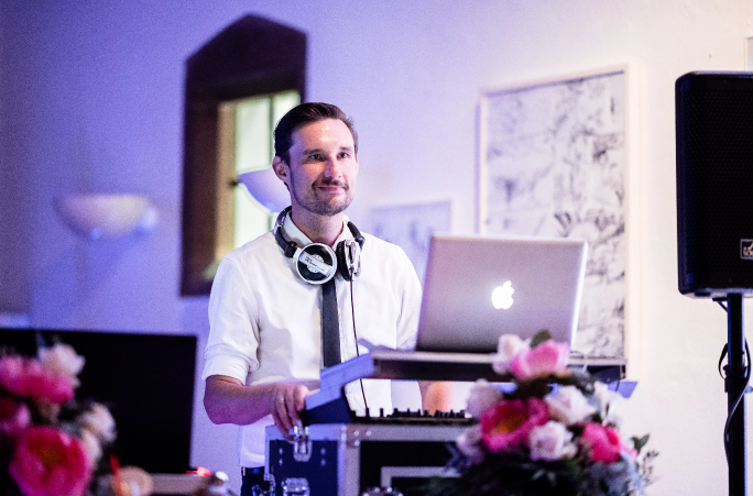 Ein Hochzeits-DJ auf einer Hochzeit mit einem Laptop vor sich.