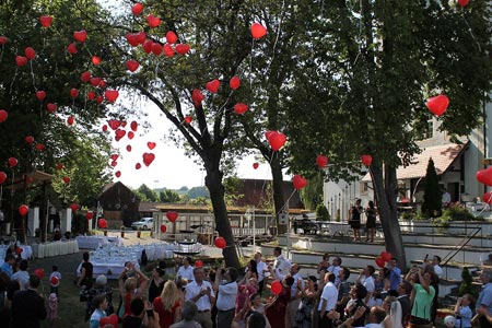 Eine Gruppe von Menschen mit roten Luftballons in der Luft feiert einen besonderen Anlass. Eine Gruppe von Menschen mit roten Luftballons in der Luft feiert einen besonderen Anlass.