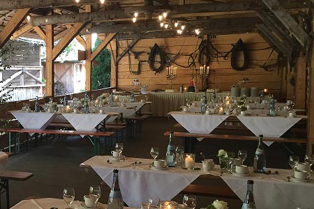 Eine Holzscheune mit Tischen und Stühlen für eine Hochzeit, perfekt für einen DJ oder Hochzeits-DJ München. Eine Holzscheune mit Tischen und Stühlen für eine Hochzeit, perfekt für einen DJ oder Hochzeits-DJ München.