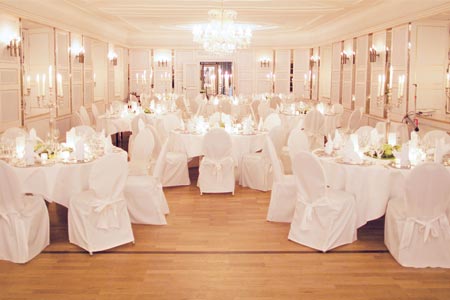 Ein großer Ballsaal mit eleganten weißen Tischdecken und funkelnden Kronleuchtern, perfekt für eine glamouröse Hochzeitsfeier. Ein großer Ballsaal mit eleganten weißen Tischdecken und funkelnden Kronleuchtern, perfekt für eine glamouröse Hochzeitsfeier.