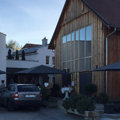 Zwei Autos parken vor einem Holzgebäude, in dem ein Hochzeits-DJ München auflegt.