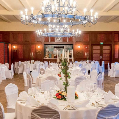 Ein Bankettsaal mit eleganter weißer Bettwäsche und funkelnden Kronleuchtern, perfekt für Hochzeiten oder besondere Anlässe.