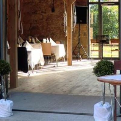 Für Veranstaltungen steht ein Raum mit Tischen und Stühlen in einer Scheune zur Verfügung. Perfekt für einen Hochzeits-DJ oder ein DJ-Setup.