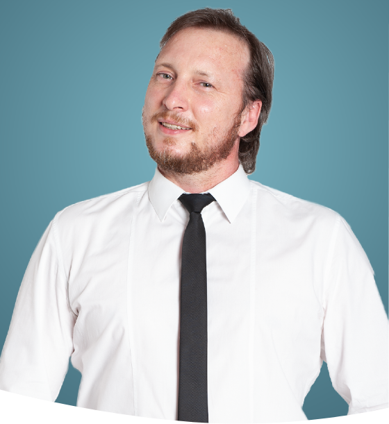 Selbstbewusster Geschäftsmann in weißem Hemd und schwarzer Krawatte, der vor blauem Hintergrund lächelt.