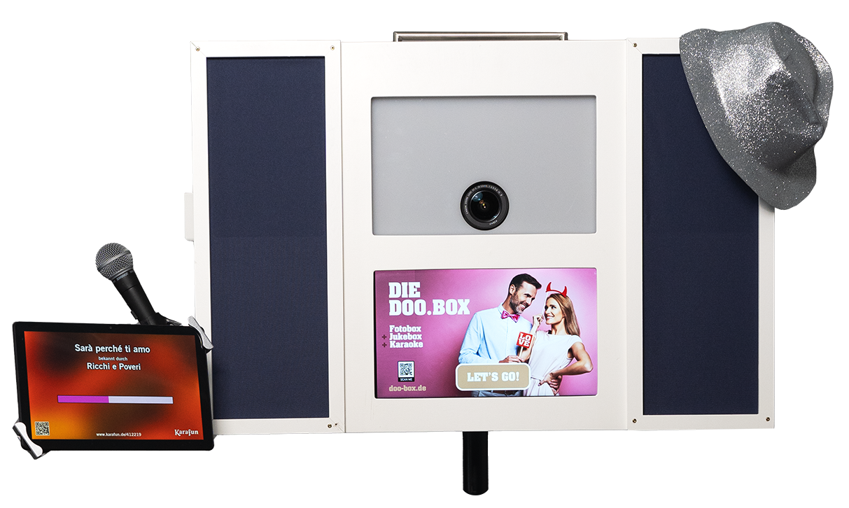 Fotokabine mit einem Bildschirm, auf dem ein Paar zu sehen ist, einem Mikrofon, einem Tablet mit Songtexten und einem silbernen Hut, der an der Seite hängt. Fotokabine mit einem Bildschirm, auf dem ein Paar zu sehen ist, einem Mikrofon, einem Tablet mit Songtexten und einem silbernen Hut, der an der Seite hängt.